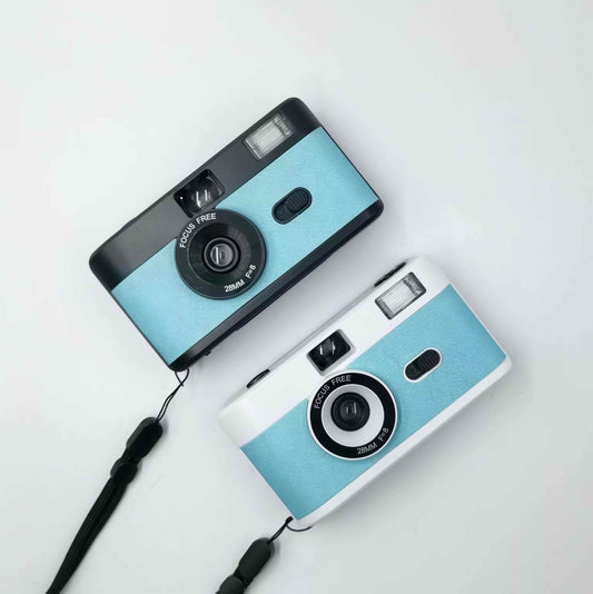 2 vintage looking film cameras blue in colour, aerial view one sits under the other. 