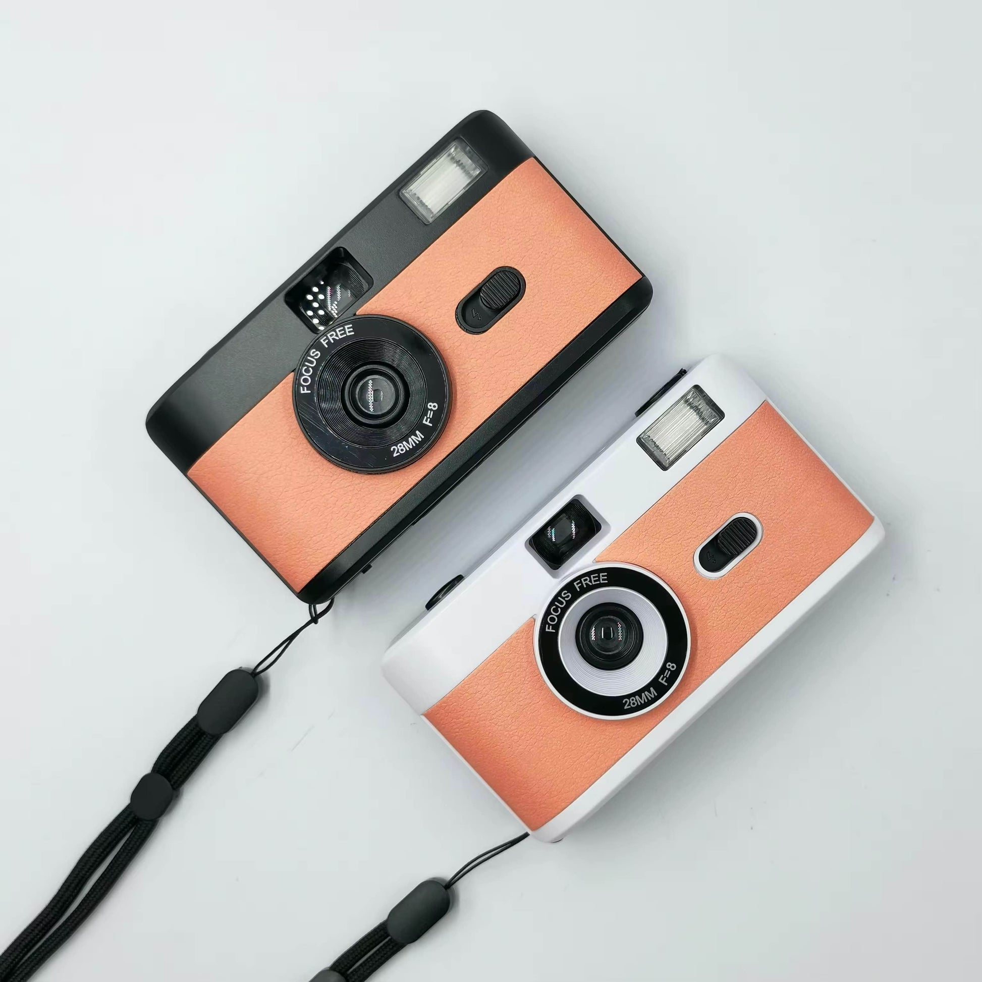 2 vintage looking film cameras a black orange one at the top and a silver orange  at the bottom, aerial view one sits under the other. Wedding accessory for guests. 