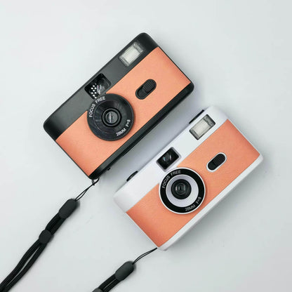 2 vintage looking film cameras a black orange one at the top and a silver orange  at the bottom, aerial view one sits under the other. Wedding accessory for guests. 