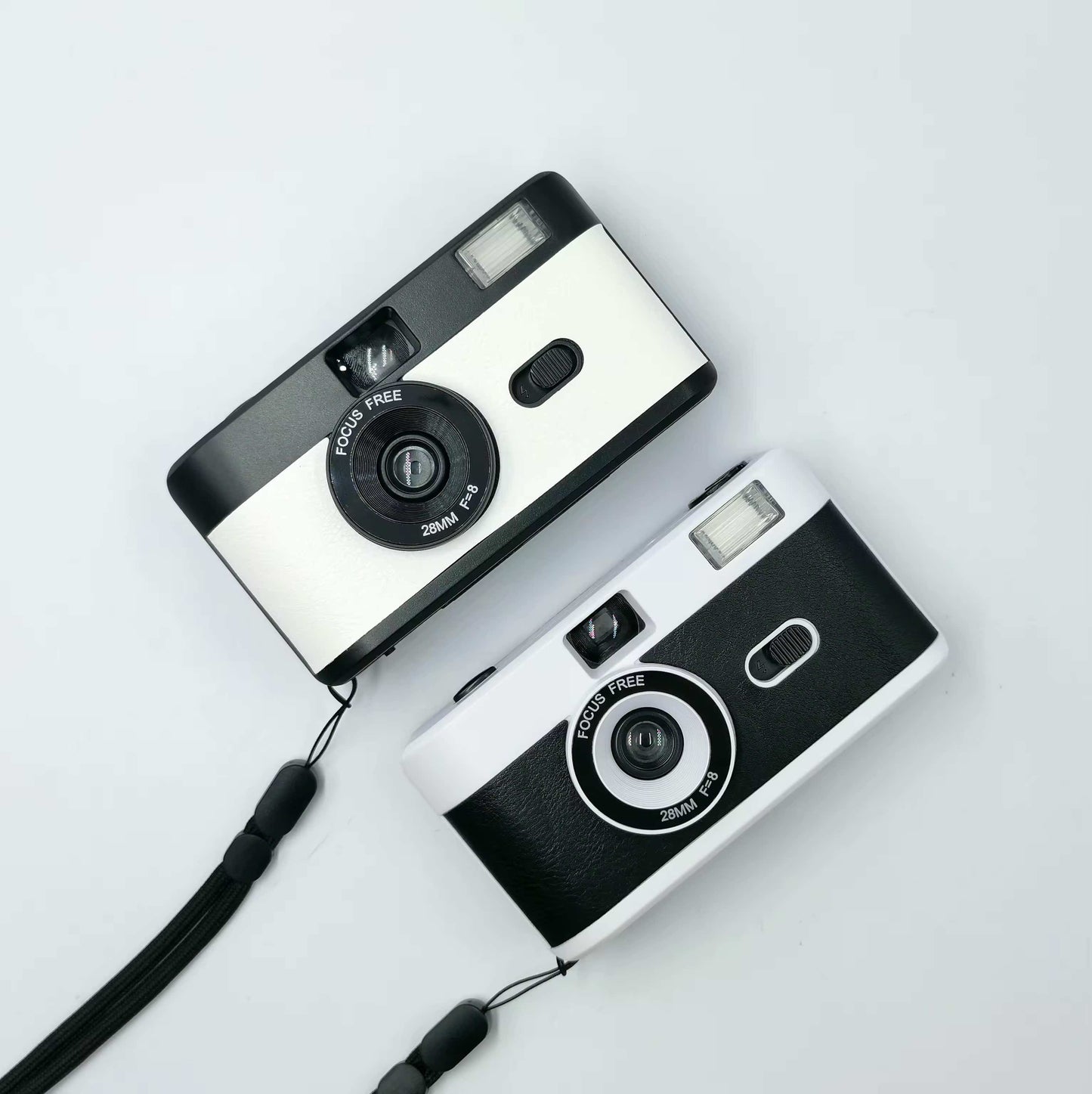 2 vintage looking film cameras a white on at the top and a black and white at the bottom, aerial view one sits under the other. 