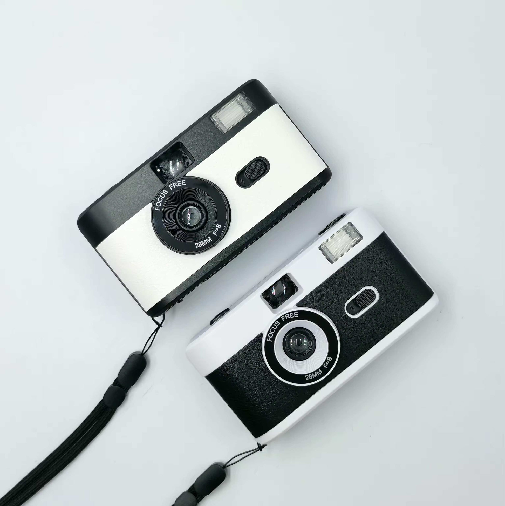 2 vintage looking film cameras a white on at the top and a black and white at the bottom, aerial view one sits under the other. 